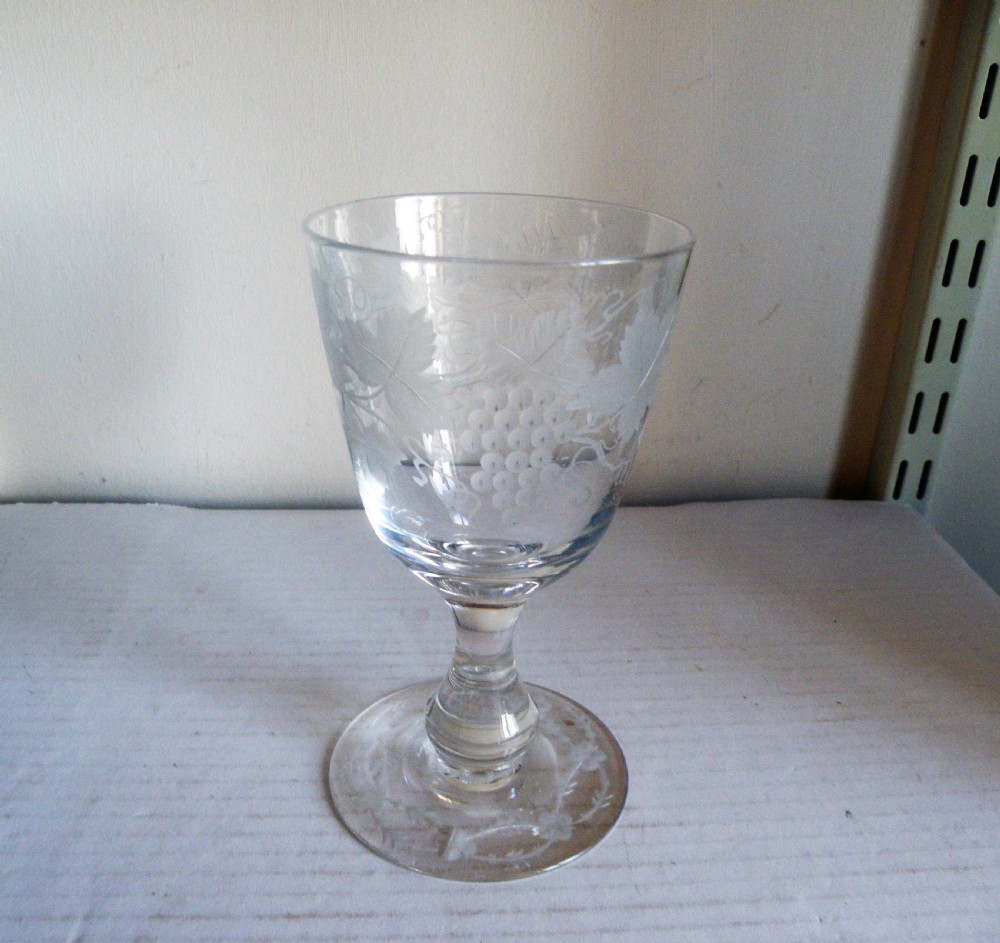 A clear Victorian glass goblet featuring wheel-engraved grapevine motifs around the bowl and a knopped stem on a flat round base. View II