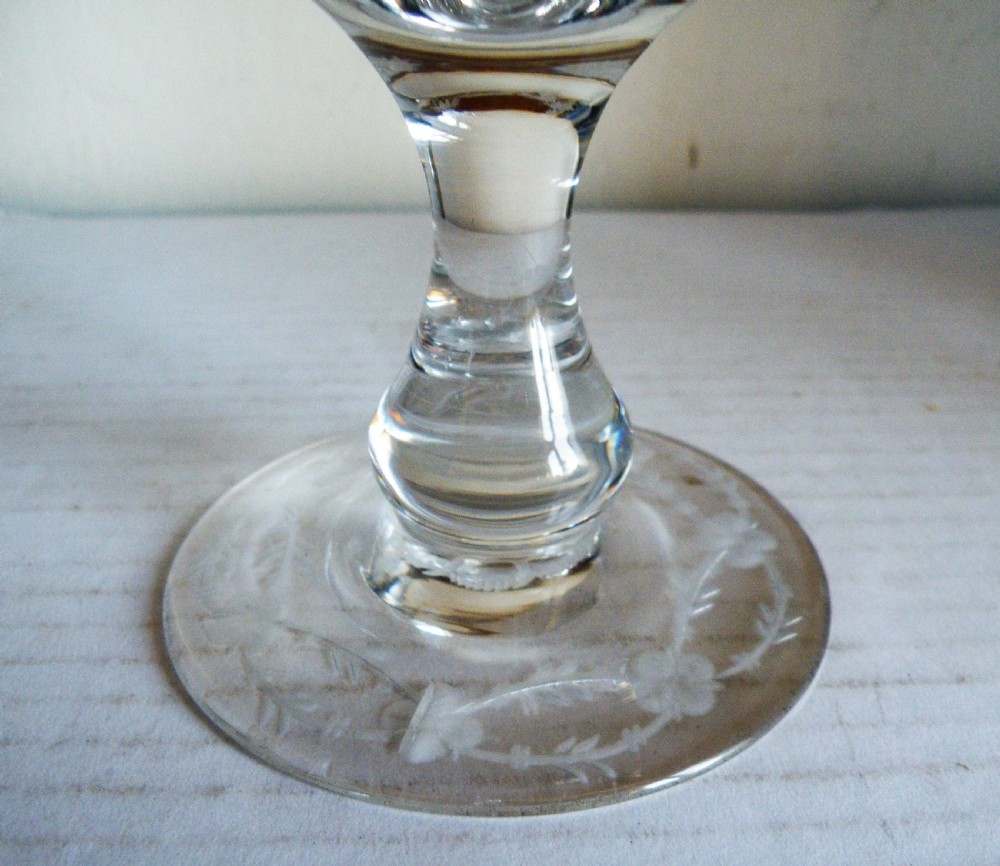 A clear Victorian glass goblet featuring wheel-engraved grapevine motifs around the bowl and a knopped stem on a flat round base. View V