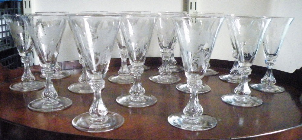 A set of eight Victorian clear cut glass sherry glasses featuring fluted bowls and slender stems arranged on a polished wood surface. View III