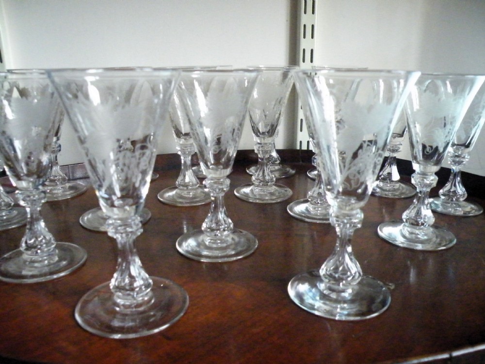 A set of eight Victorian clear cut glass sherry glasses featuring fluted bowls and slender stems arranged on a polished wood surface. View V