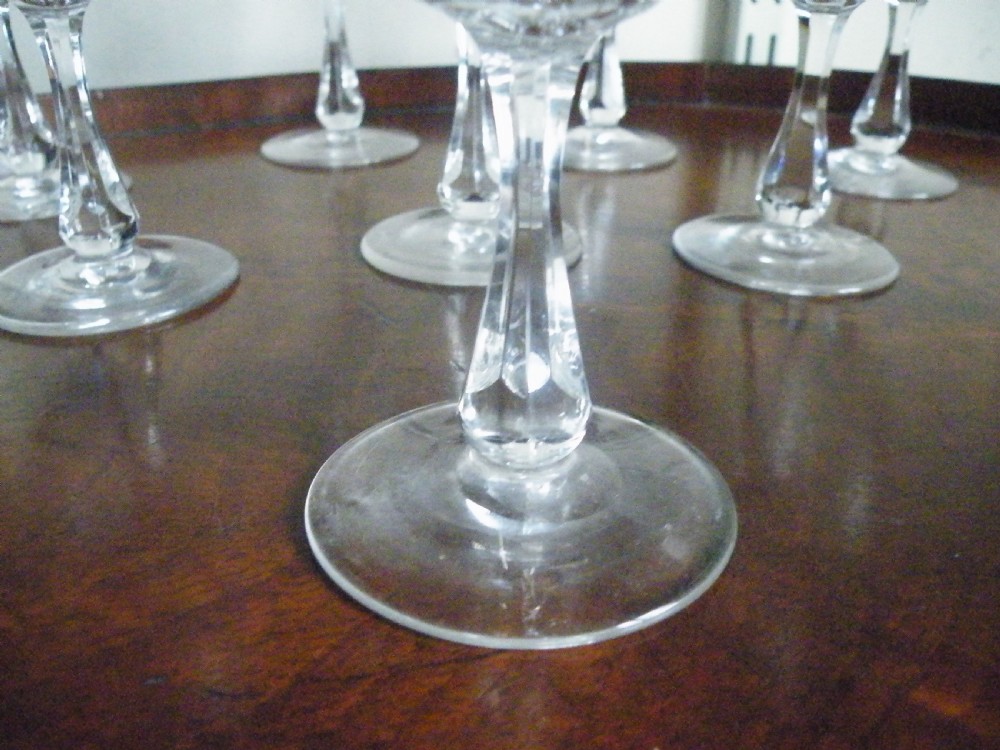 A set of eight Victorian clear cut glass sherry glasses featuring fluted bowls and slender stems arranged on a polished wood surface. View VII