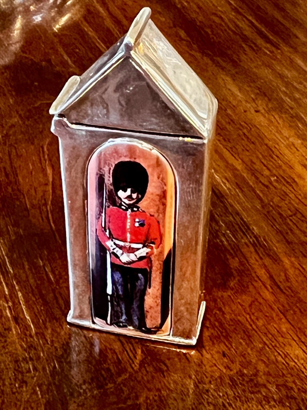 A small vertical silver vesta case shaped like a sentry box, featuring a painted enamel depiction of a guardsman on the front.