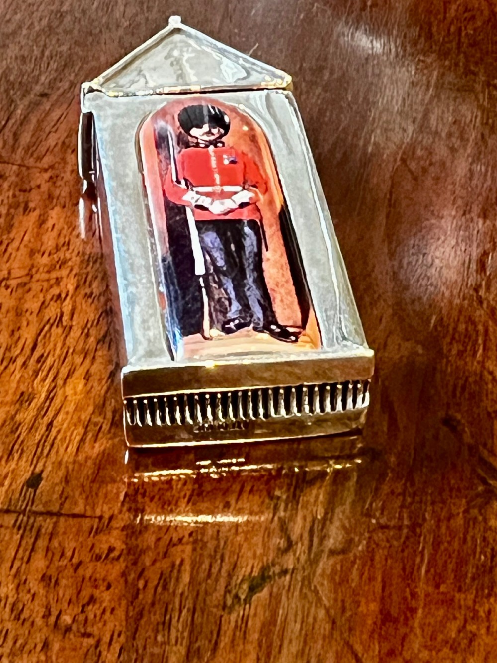 A small vertical silver vesta case shaped like a sentry box, featuring a painted enamel depiction of a guardsman on the front. View VII