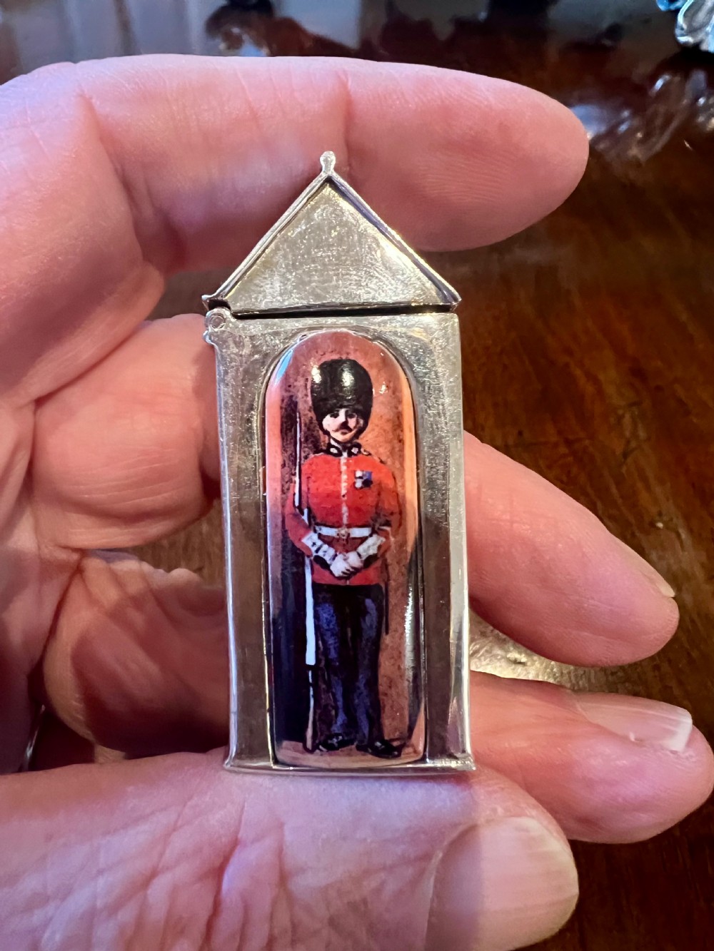 A small vertical silver vesta case shaped like a sentry box, featuring a painted enamel depiction of a guardsman on the front. View IX