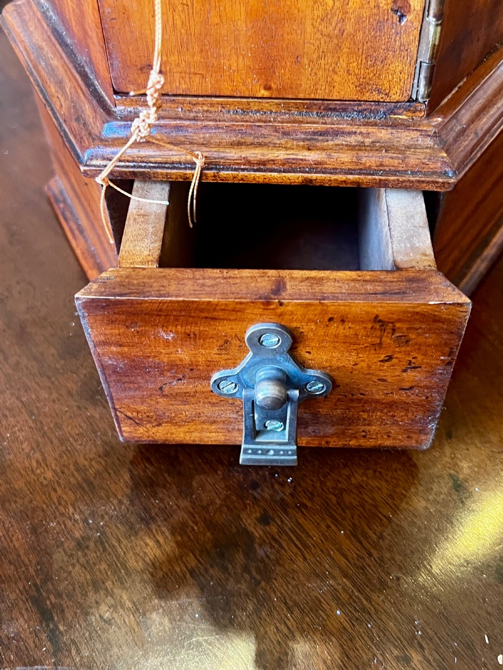 An octagonal wooden postal box featuring carved detailing on the domed roof, a brass letter slot, and a hinged locking door. View VII
