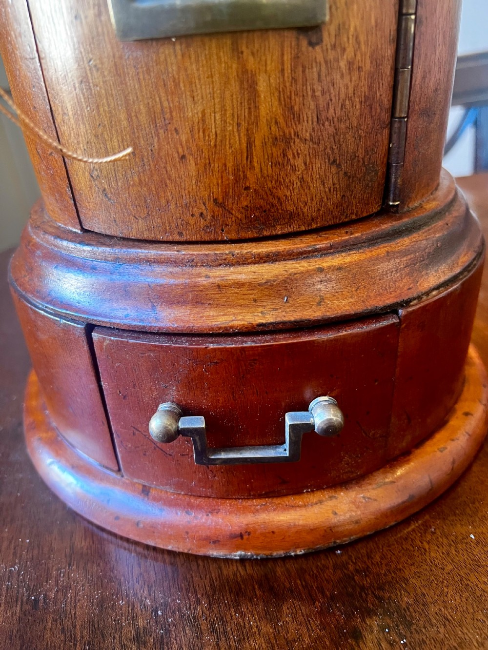 A cylindrical wooden post box featuring a brass letter slot, a small door with a key, and a lower drawer with a metal handle. View VI