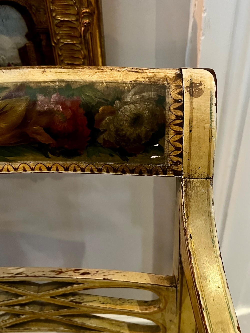 A Regency period cream painted elbow chair featuring hand-painted crest rail decoration, a geometric lattice back, sweeping arms, turned front legs, and a woven cane seat. View III