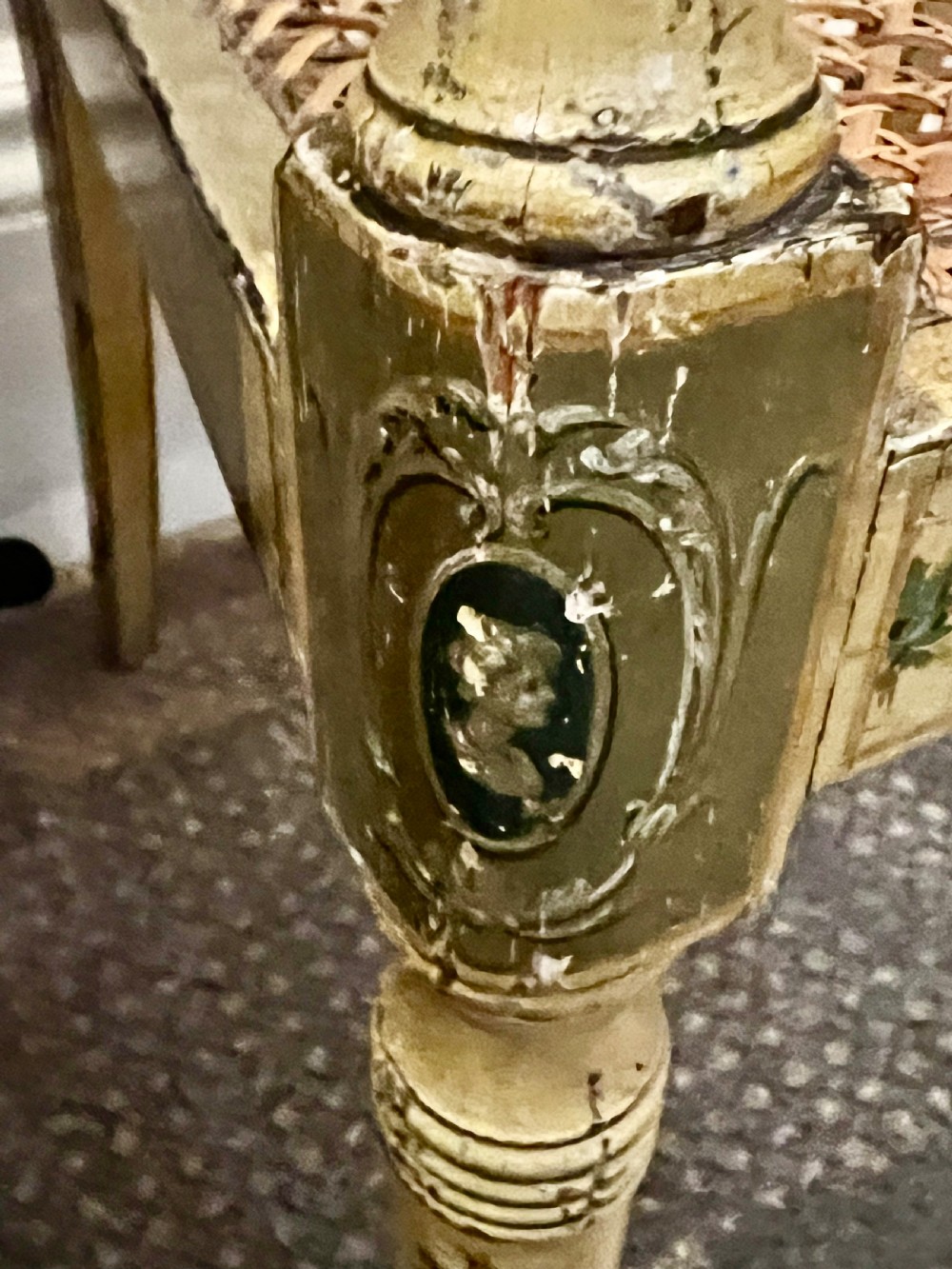 A Regency period cream painted elbow chair featuring hand-painted crest rail decoration, a geometric lattice back, sweeping arms, turned front legs, and a woven cane seat. View V