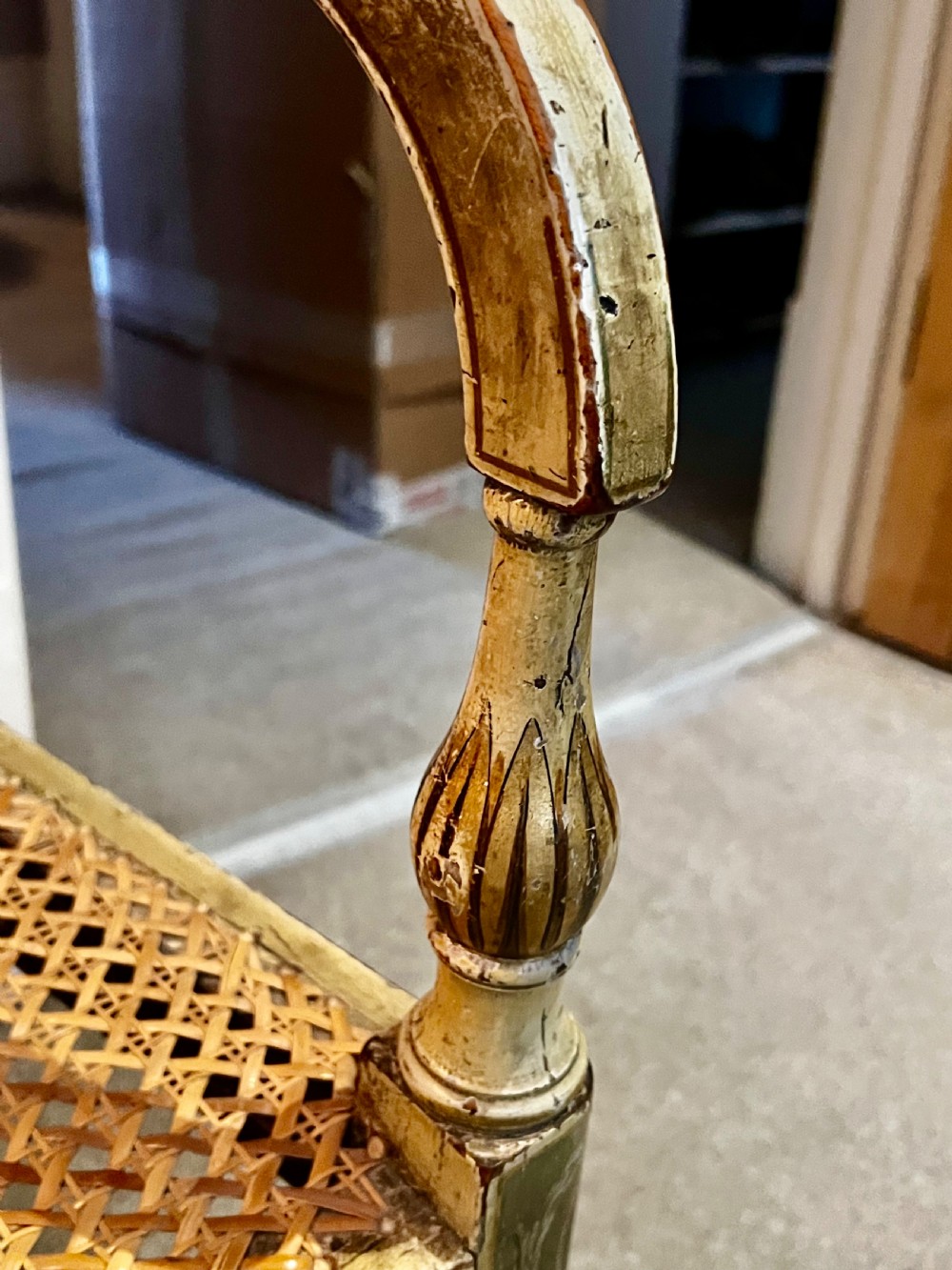 A Regency period cream painted elbow chair featuring hand-painted crest rail decoration, a geometric lattice back, sweeping arms, turned front legs, and a woven cane seat. View VIII