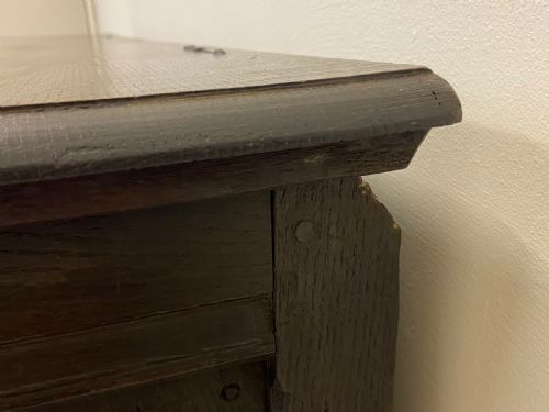 fig 1. An 18th-century dark oak coffer with a flat rectangular top and four recessed front panels resting on extended stile feet.
