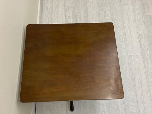 fig 1. A square dark mahogany tilt-top table featuring a central turned stem supported by three cabriole legs with pad feet.