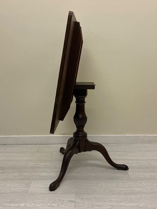 fig 2. A square dark mahogany tilt-top table featuring a central turned stem supported by three cabriole legs with pad feet.