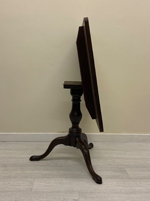 fig 3. A square dark mahogany tilt-top table featuring a central turned stem supported by three cabriole legs with pad feet.
