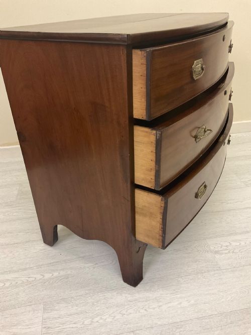fig 4. A Victorian mahogany chest of drawers featuring three curved bow-front drawers, brass hardware, and shaped feet.