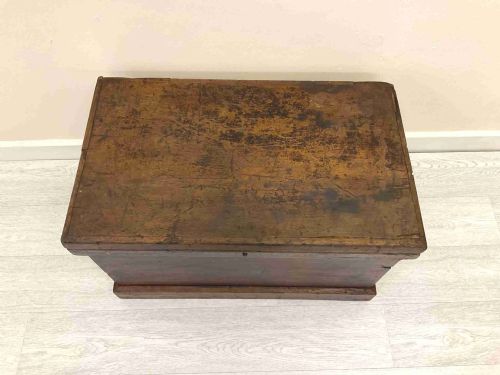 fig 4. A rectangular 19th-century Victorian pine trunk featuring a dark brown finish, hinged flat lid, central keyhole, and plinth base.