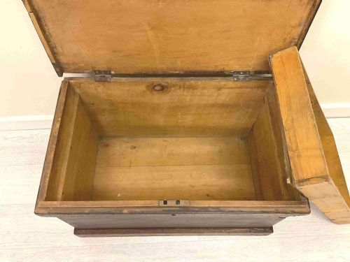 fig 5. A rectangular 19th-century Victorian pine trunk featuring a dark brown finish, hinged flat lid, central keyhole, and plinth base.