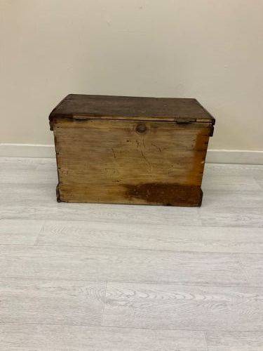 fig 7. A rectangular 19th-century Victorian pine trunk featuring a dark brown finish, hinged flat lid, central keyhole, and plinth base.