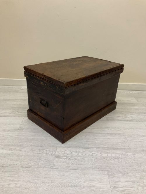 fig 8. A rectangular 19th-century Victorian pine trunk featuring a dark brown finish, hinged flat lid, central keyhole, and plinth base.