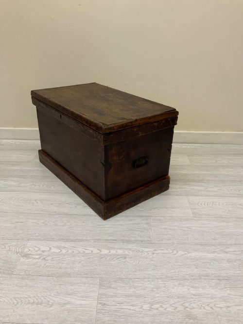 fig 9. A rectangular 19th-century Victorian pine trunk featuring a dark brown finish, hinged flat lid, central keyhole, and plinth base.