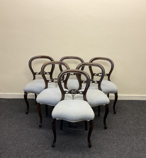 fig 1. A set of six Victorian mahogany dining chairs featuring rounded balloon backs, central carved splats, light blue upholstered seats, and cabriole front legs.