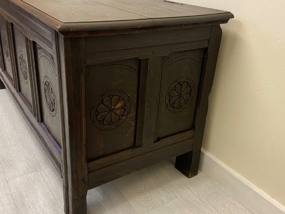 An 18th-century dark oak coffer with a flat rectangular top and four recessed front panels resting on extended stile feet. View XII