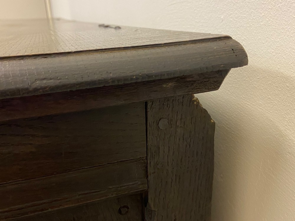An 18th-century dark oak coffer with a flat rectangular top and four recessed front panels resting on extended stile feet. View II