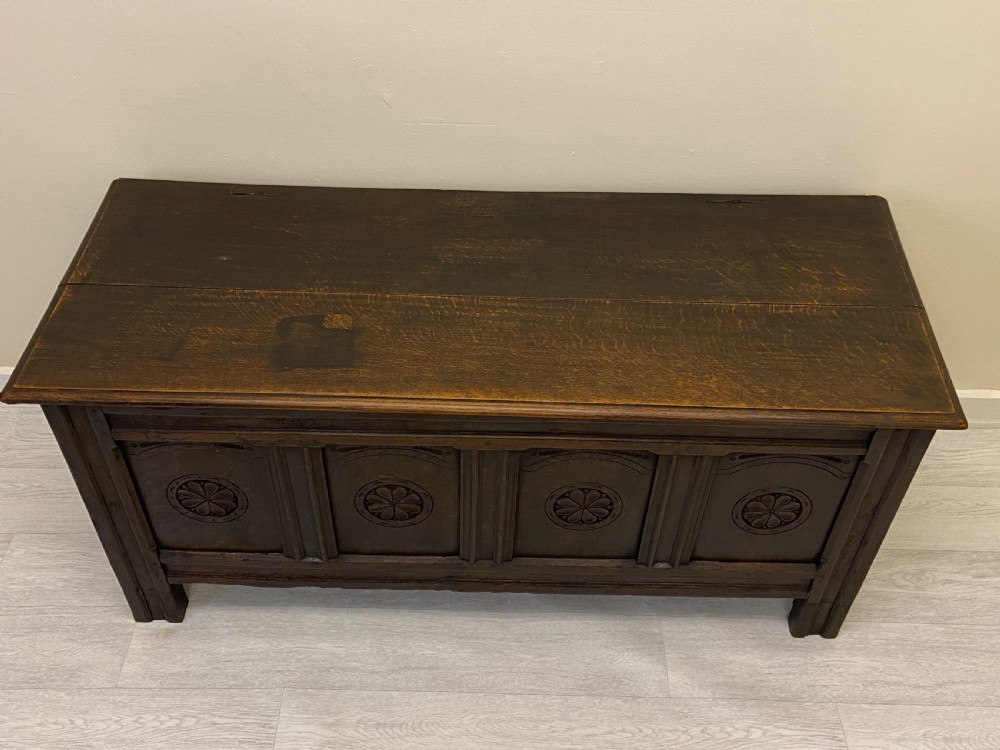 An 18th-century dark oak coffer with a flat rectangular top and four recessed front panels resting on extended stile feet. View V