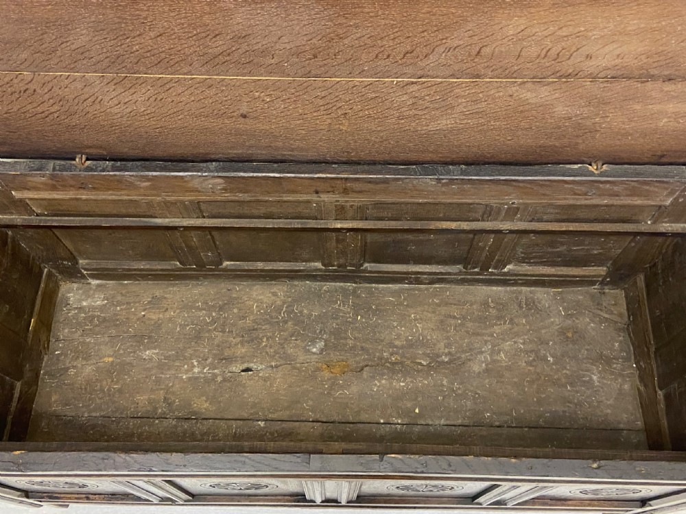 An 18th-century dark oak coffer with a flat rectangular top and four recessed front panels resting on extended stile feet. View IX