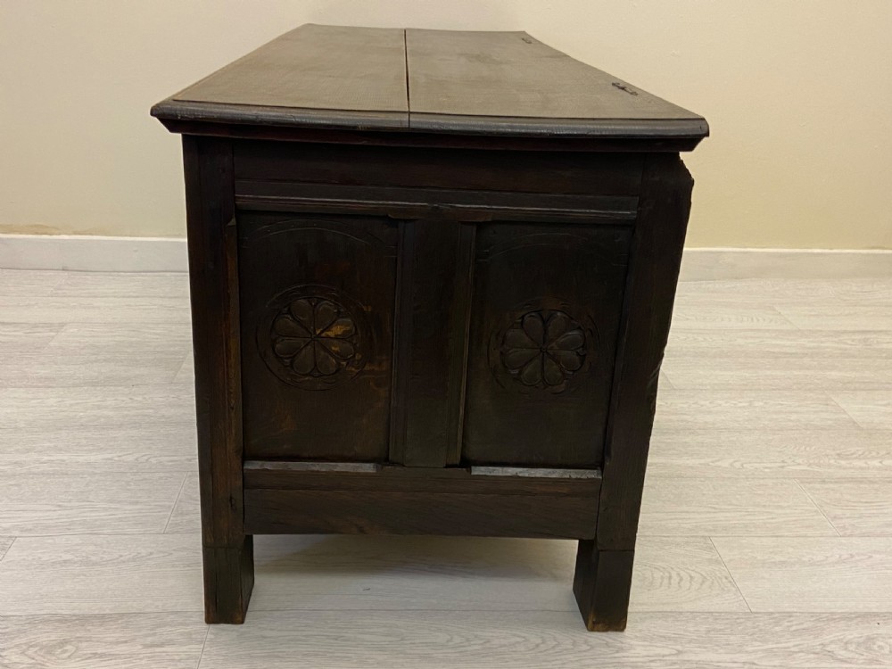 An 18th-century dark oak coffer with a flat rectangular top and four recessed front panels resting on extended stile feet. View XI