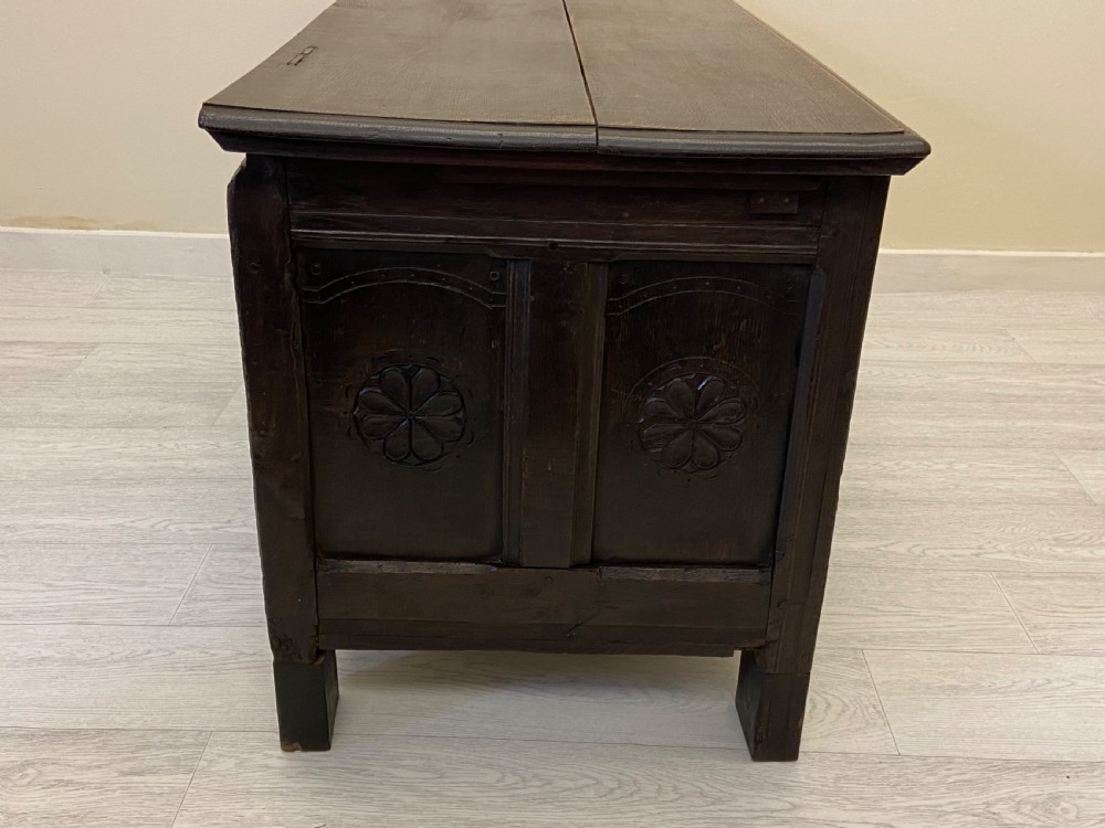 An 18th-century dark oak coffer with a flat rectangular top and four recessed front panels resting on extended stile feet. View XIII