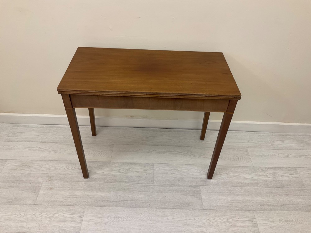 An Edwardian mahogany fold-over tea table with straight tapered legs and a rectangular hinged top shown in a closed position against a plain neutral background.