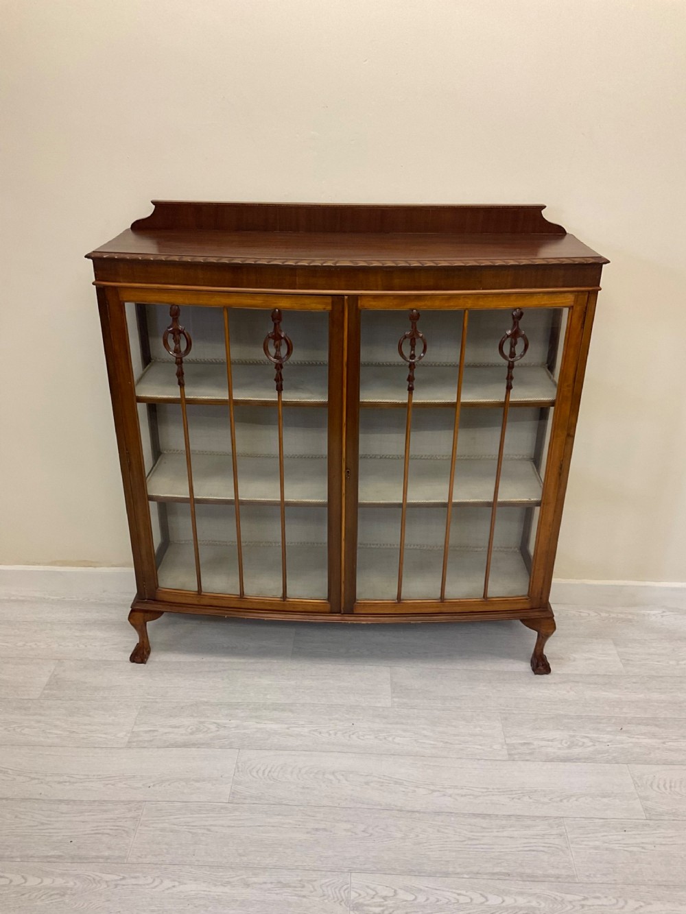 An early 20th-century mahogany glazed display cabinet with decorative astragal glazing bars, cabriole legs, and ball-and-claw feet.