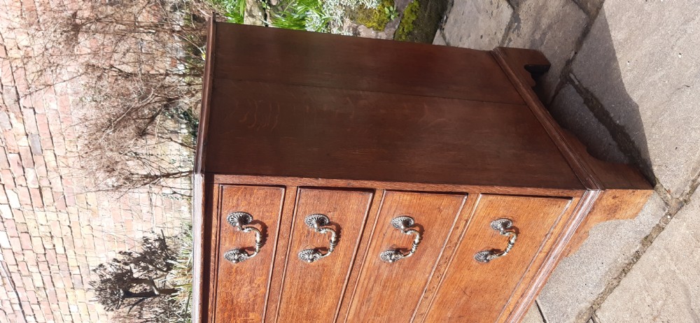 A Georgian oak chest of drawers featuring four full-width drawers with brass handles and keyhole escutcheons, resting on bracket feet. View II