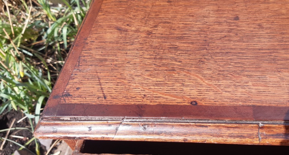 A Georgian oak chest of drawers featuring four full-width drawers with brass handles and keyhole escutcheons, resting on bracket feet. View VIII