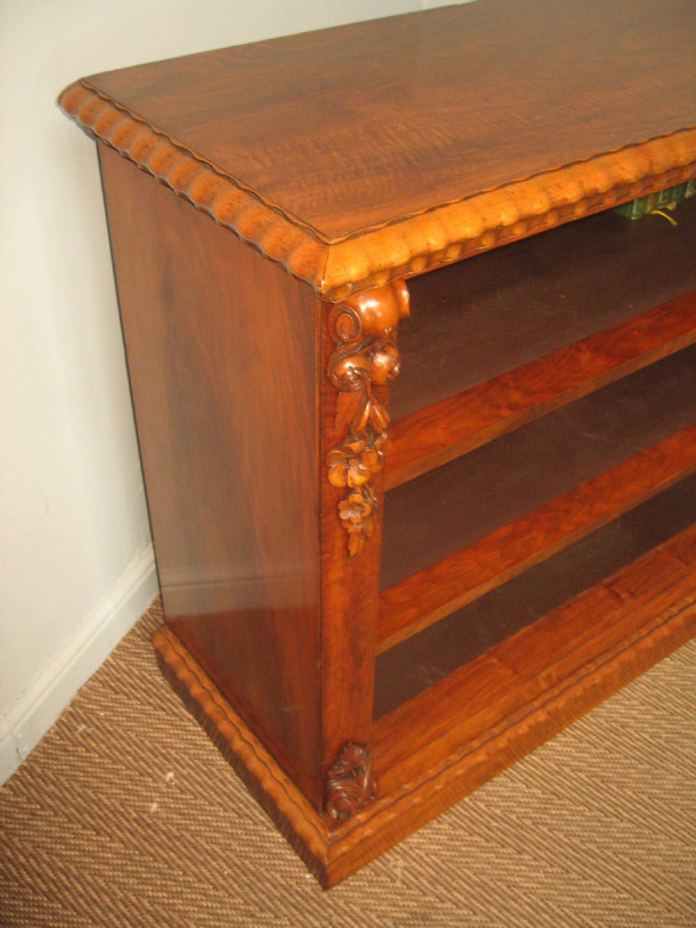 A Victorian open walnut bookcase featuring three shelves and carved floral corbels on side pilasters. View III