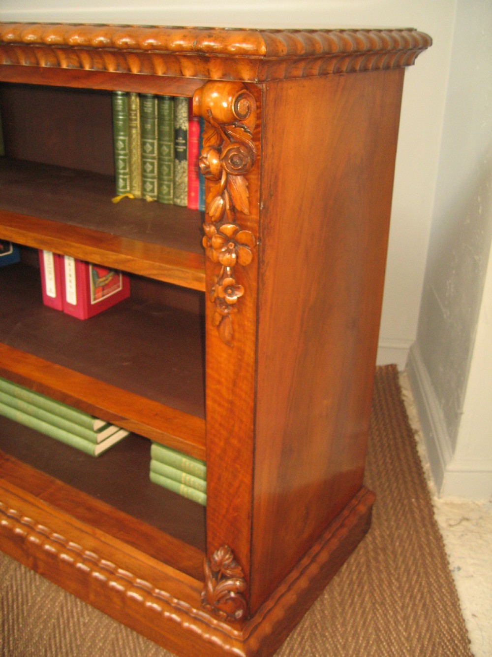 A Victorian open walnut bookcase featuring three shelves and carved floral corbels on side pilasters. View V