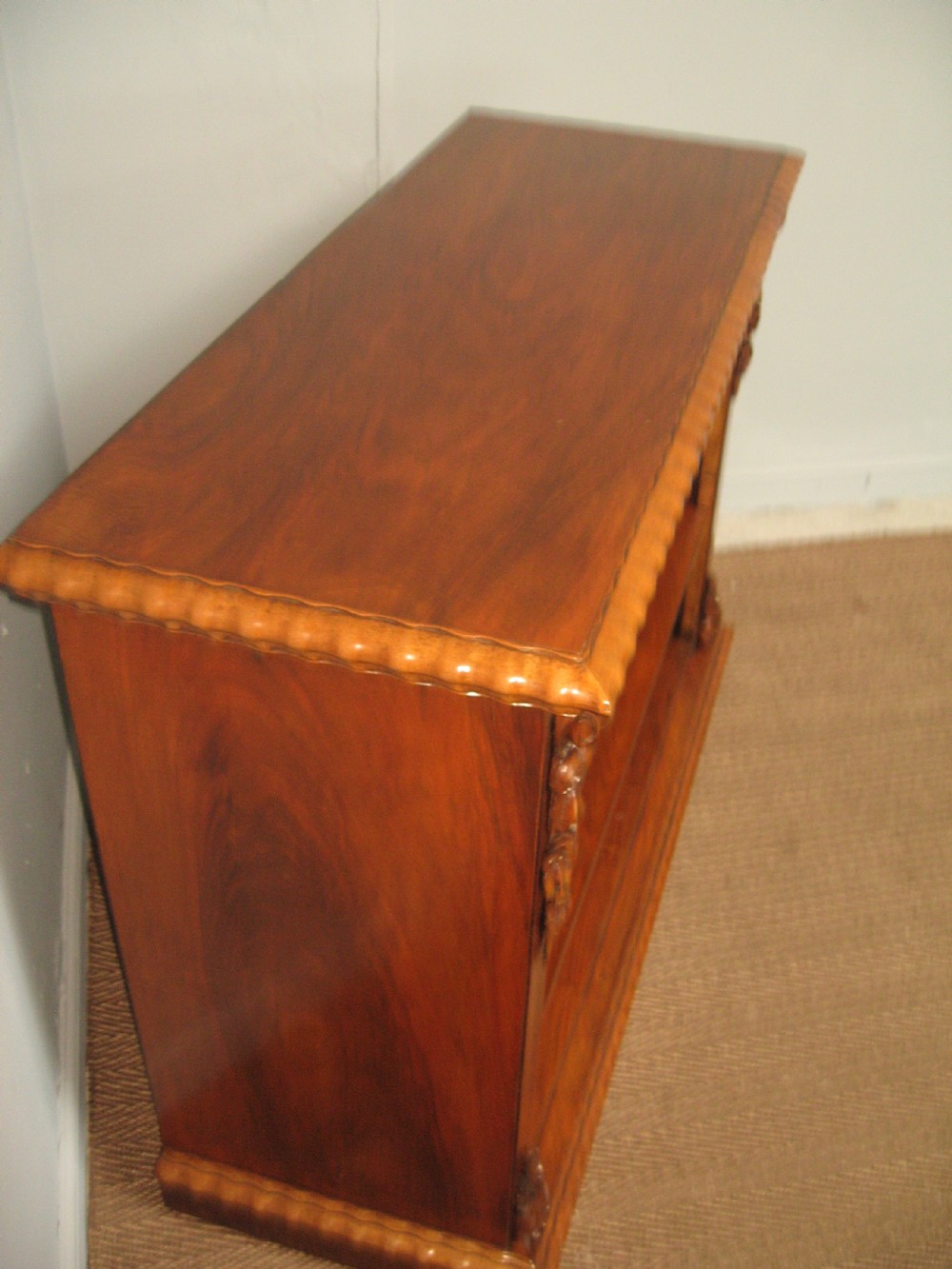 A Victorian open walnut bookcase featuring three shelves and carved floral corbels on side pilasters. View VIII