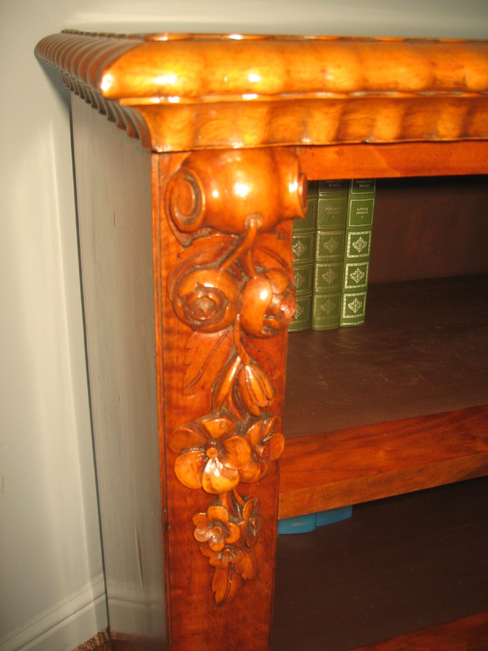 A Victorian open walnut bookcase featuring three shelves and carved floral corbels on side pilasters. View X