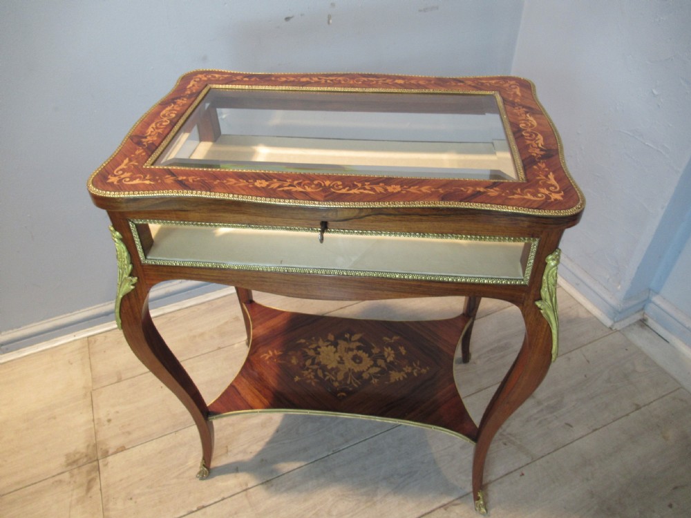 A 19th-century French rosewood bijouterie table featuring a glazed lift top, floral marquetry inlay, gilt bronze mounts, cabriole legs, and a lower shelf. View II