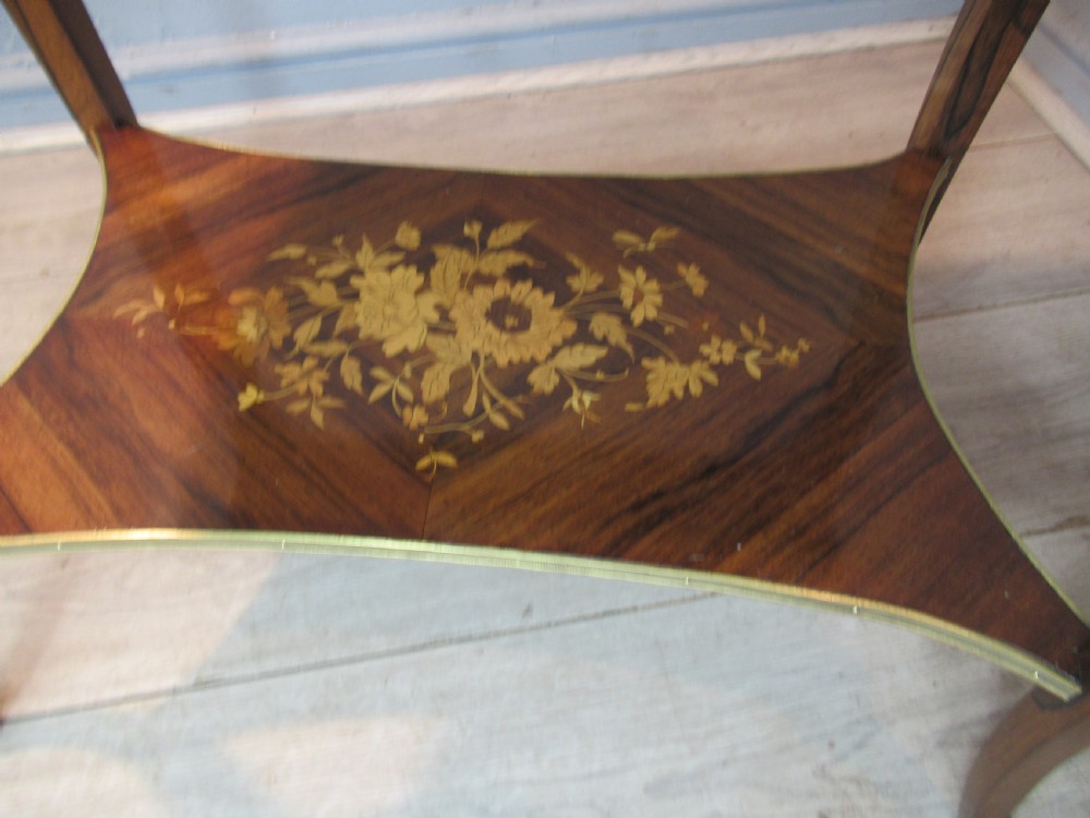 A 19th-century French rosewood bijouterie table featuring a glazed lift top, floral marquetry inlay, gilt bronze mounts, cabriole legs, and a lower shelf. View V