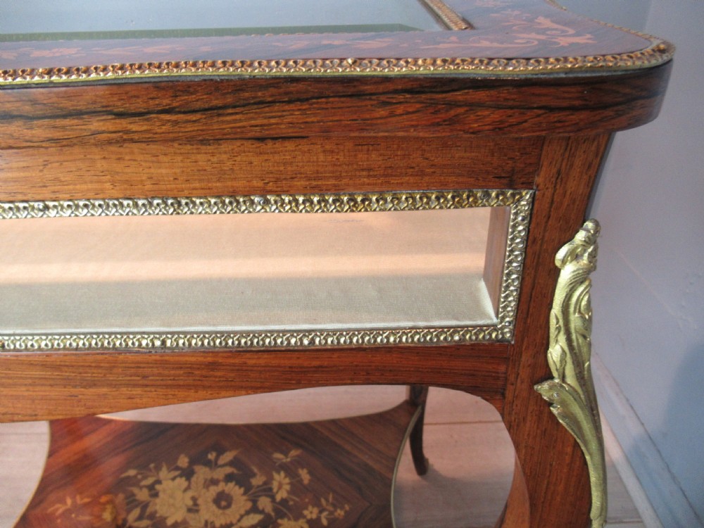 A 19th-century French rosewood bijouterie table featuring a glazed lift top, floral marquetry inlay, gilt bronze mounts, cabriole legs, and a lower shelf. View VIII