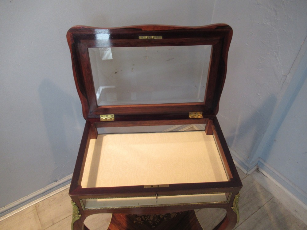 A 19th-century French rosewood bijouterie table featuring a glazed lift top, floral marquetry inlay, gilt bronze mounts, cabriole legs, and a lower shelf. View XII