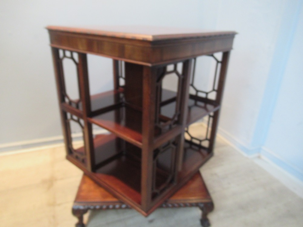 A square dark mahogany revolving bookcase featuring two tiers, fretwork side panels, and carved ball and claw feet. View III
