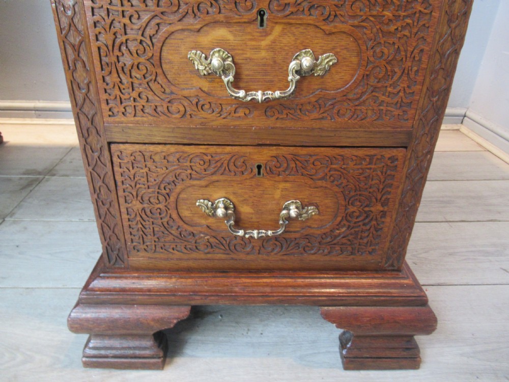 A late Victorian carved oak kneehole pedestal desk featuring nine drawers with relief carving and brass handles. View X