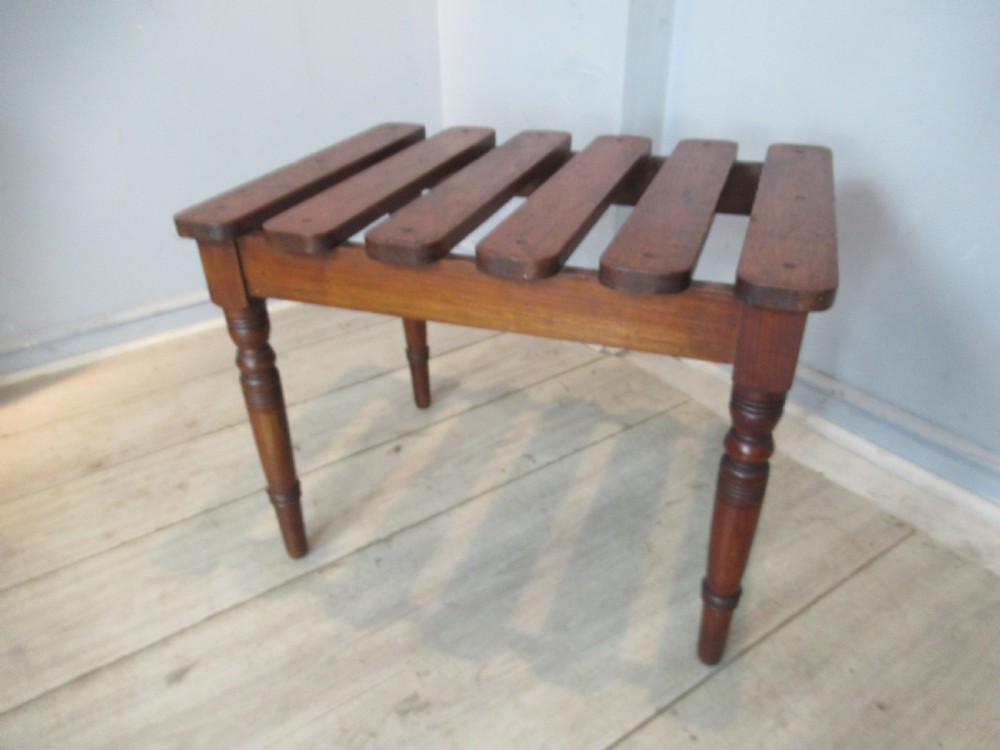 A late Victorian mahogany luggage stand featuring six rounded slatted top rails supported by a sturdy timber frame and four turned legs. View V