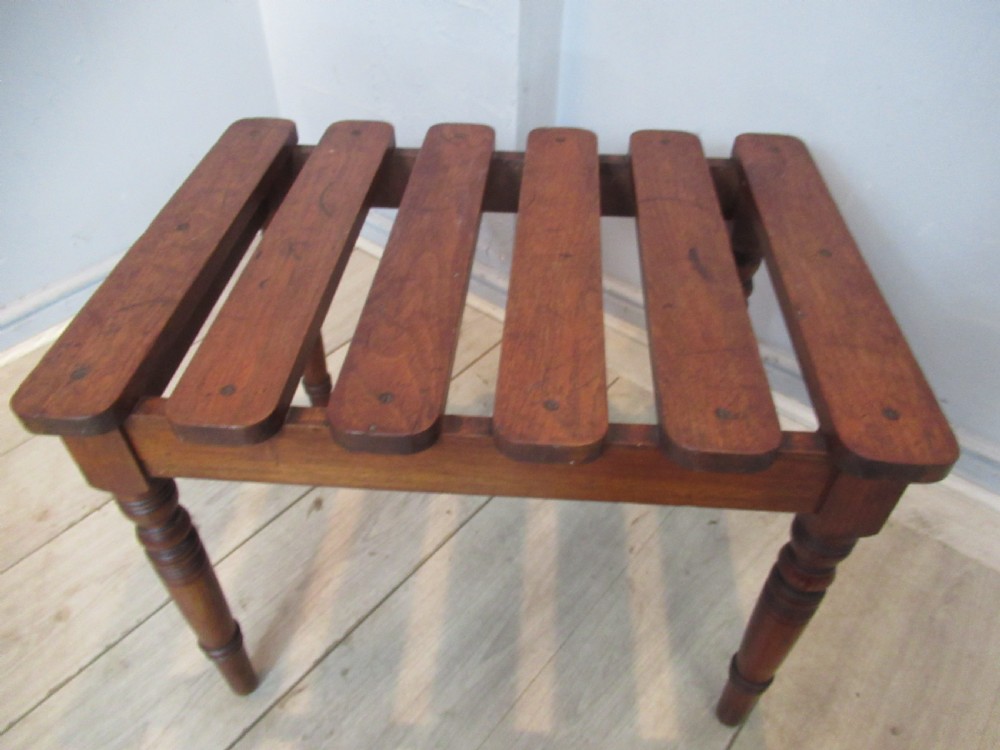 A late Victorian mahogany luggage stand featuring six rounded slatted top rails supported by a sturdy timber frame and four turned legs. View VII