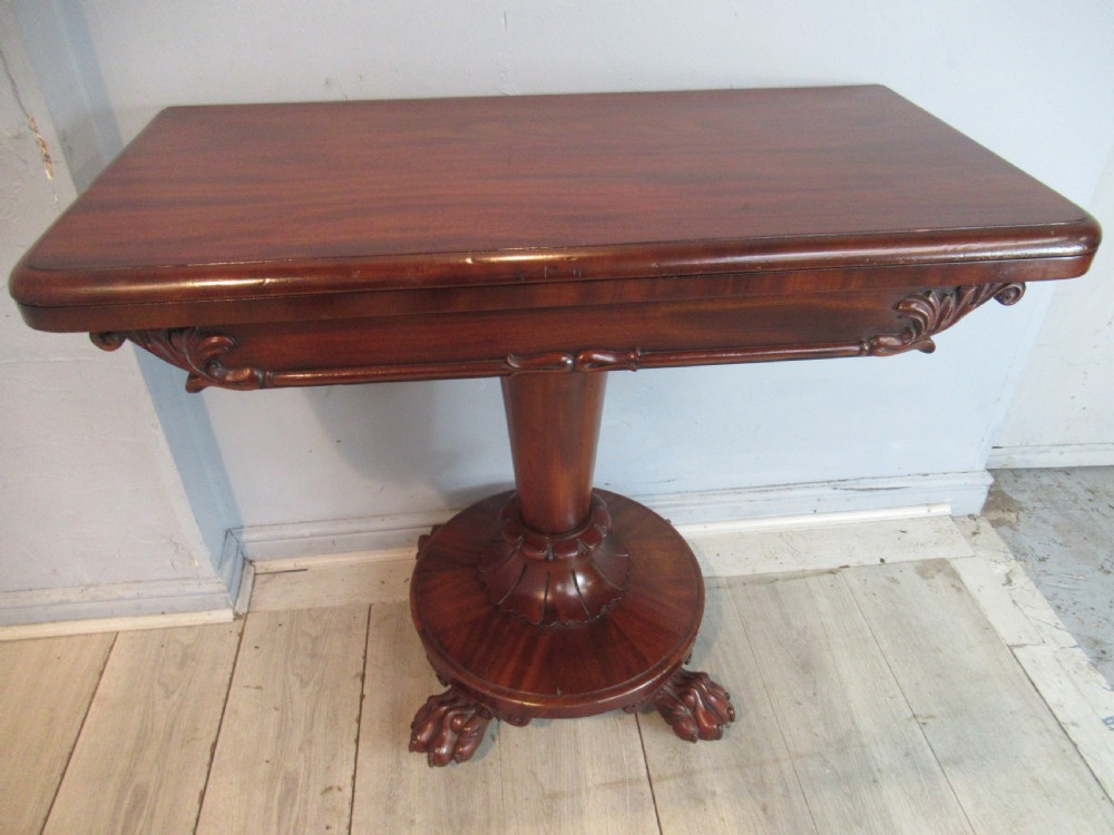A Victorian mahogany card table featuring a rectangular fold-over top, a central turned pedestal, and carved paw feet on a circular platform base. View II