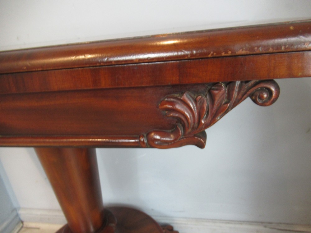 A Victorian mahogany card table featuring a rectangular fold-over top, a central turned pedestal, and carved paw feet on a circular platform base. View V