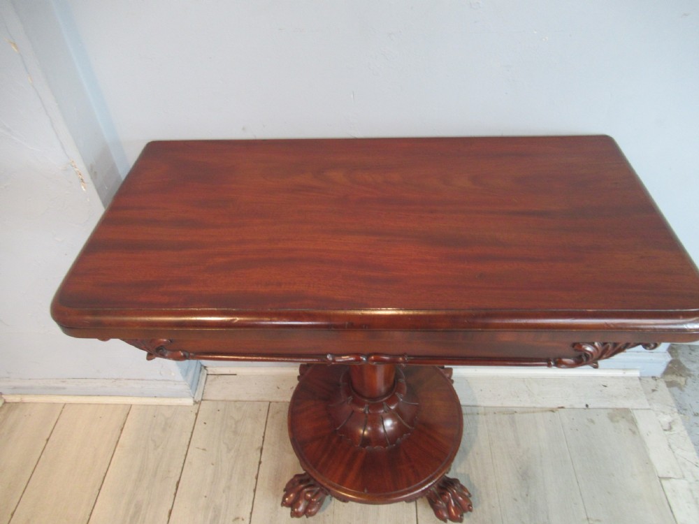 A Victorian mahogany card table featuring a rectangular fold-over top, a central turned pedestal, and carved paw feet on a circular platform base. View VI