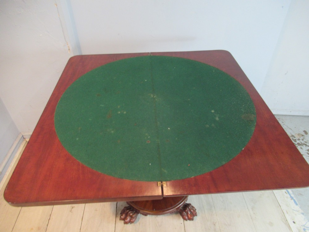 A Victorian mahogany card table featuring a rectangular fold-over top, a central turned pedestal, and carved paw feet on a circular platform base. View VIII